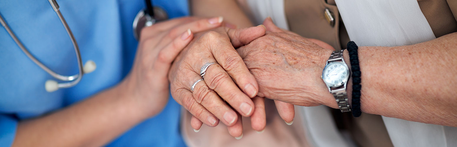 closeup of caregiver and eldery woman's hands
